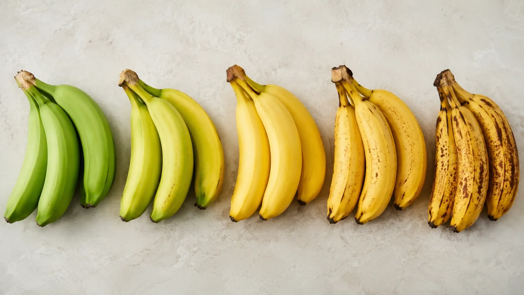 Bananas em diferentes estágios de maturação, passando do verde ao amarelo com manchas marrons.