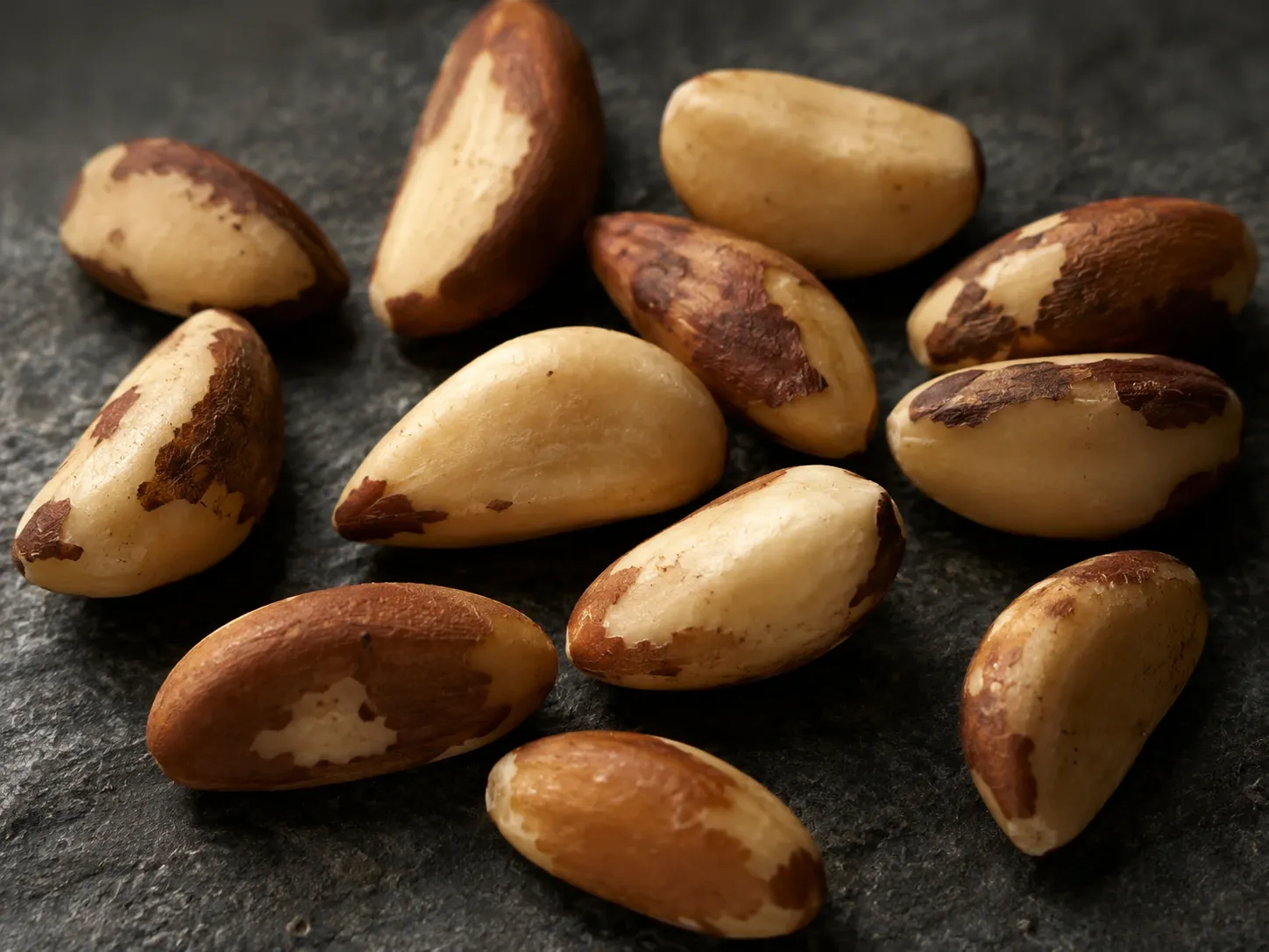 Castanhas-do-brasil de diferentes tamanhos sobre uma superfície escura, representando a variabilidade natural do alimento.